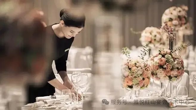 酒店服务员用粉红玫瑰、插花布置正式宴会桌